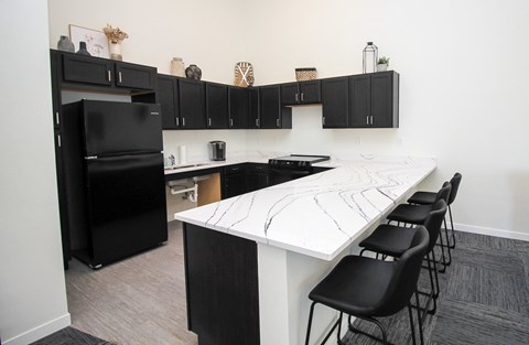 A kitchen with black cabinets and a white island.