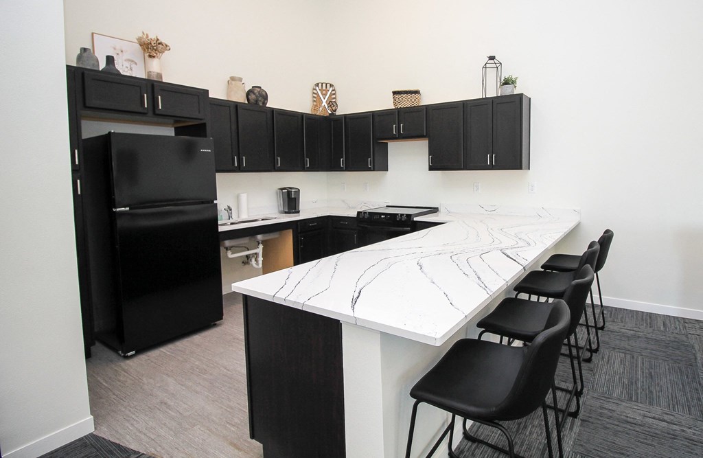 A kitchen with black cabinets and a white island.