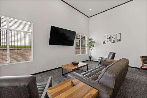 A living room with a brown leather couch, a wooden coffee table, and a flat screen TV mounted on the wall.