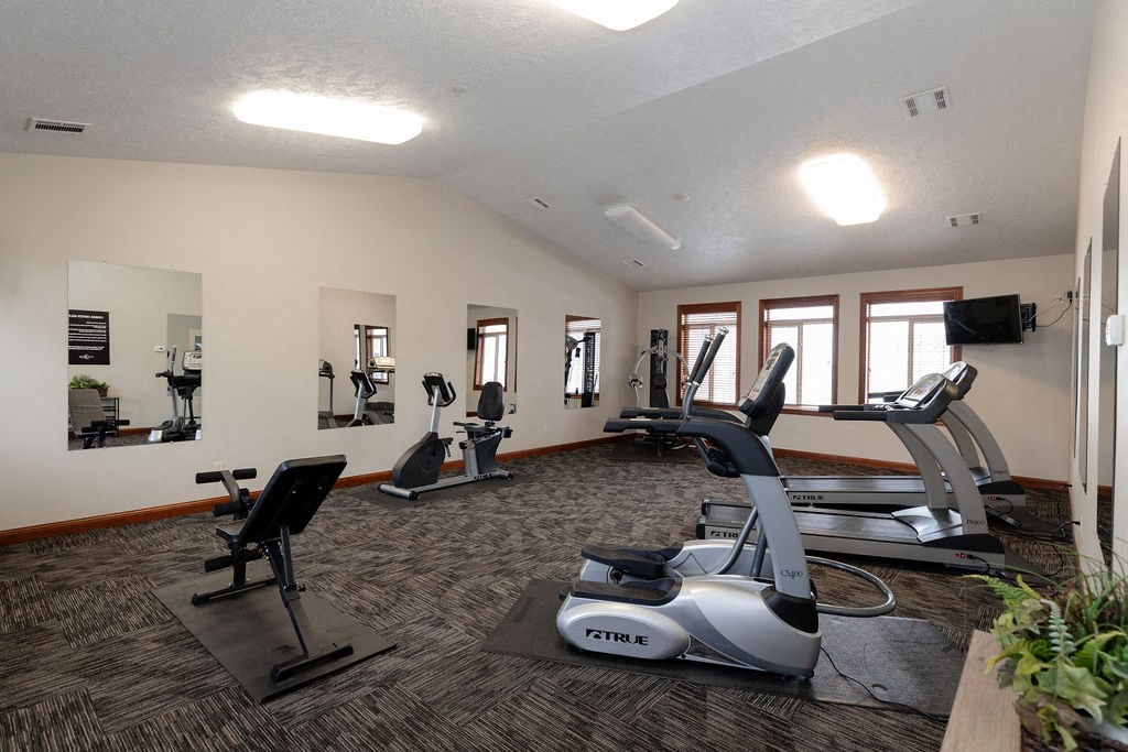a gym with treadmills and other exercise equipment in a large room with windows