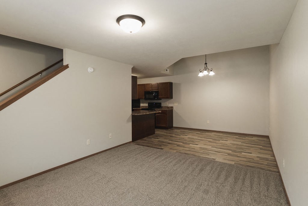 an empty living room with a kitchen in the corner
