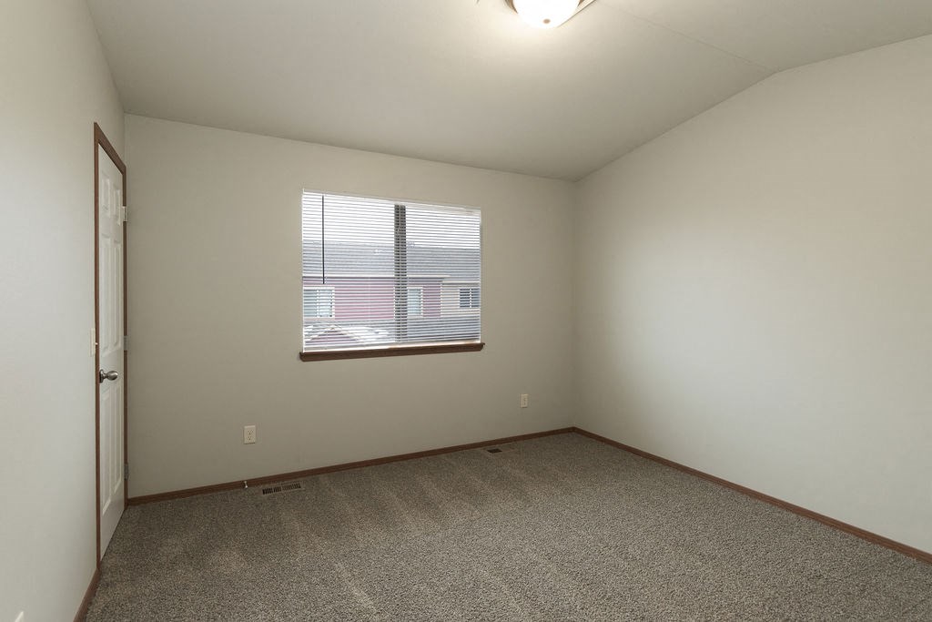 an empty living room with a window and carpet
