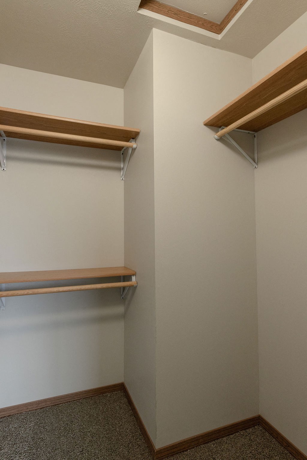 a walk in closet with shelves and a hanger on the wall