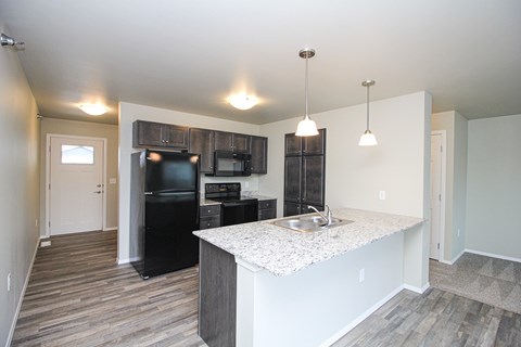 A kitchen with a black refrigerator and a sink.