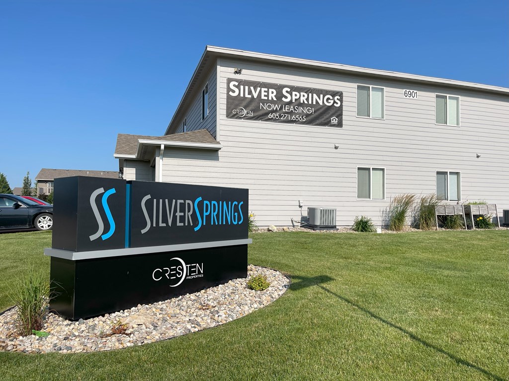A sign for Silver Springs leasing office in front of a building.