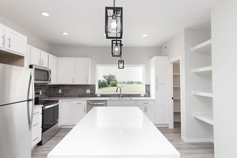 an open kitchen with white cabinets and a white counter top