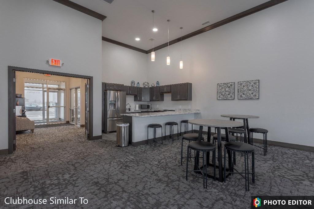 a communal area with a kitchen and bar and chairs and a table with stools