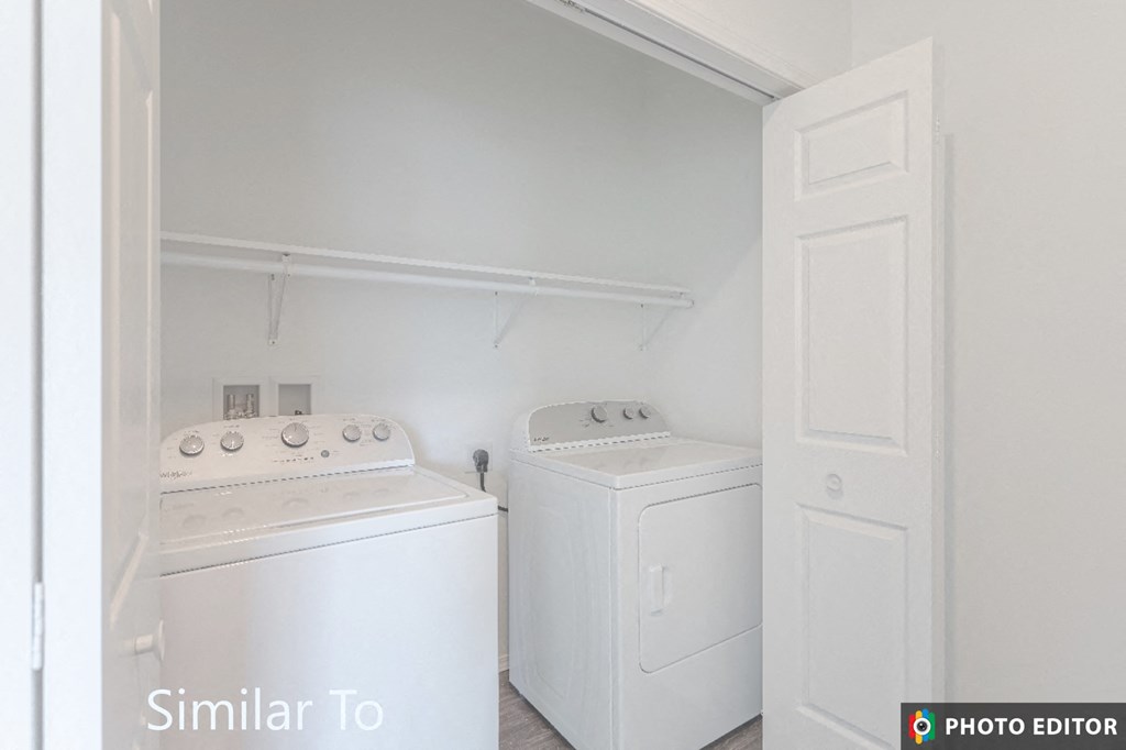 a white laundry room with two white machines and a white door