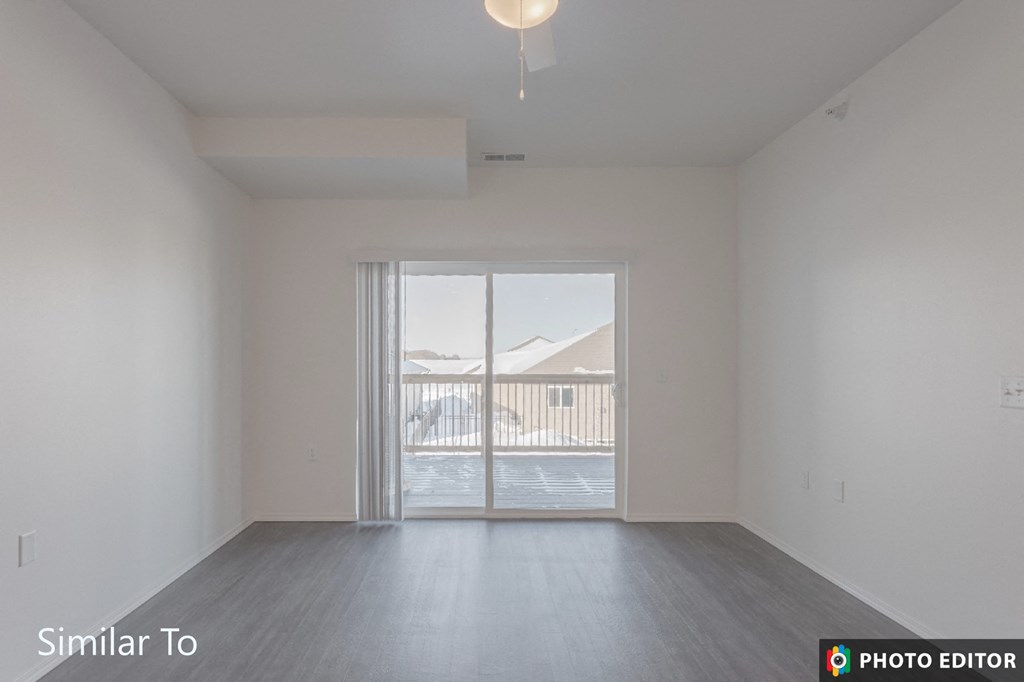 an empty living room with a sliding glass door to a balcony