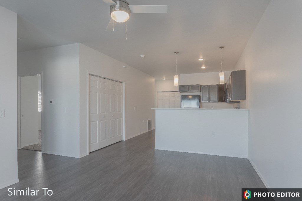 an empty living room and kitchen with white walls and wood flooring
