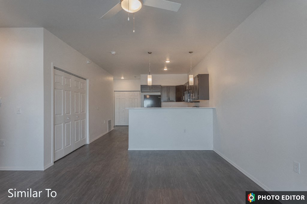 an empty living room and kitchen with white walls and wood flooring