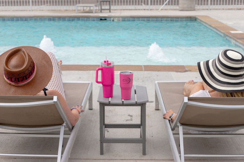 two women sitting in deck chairs near a pool