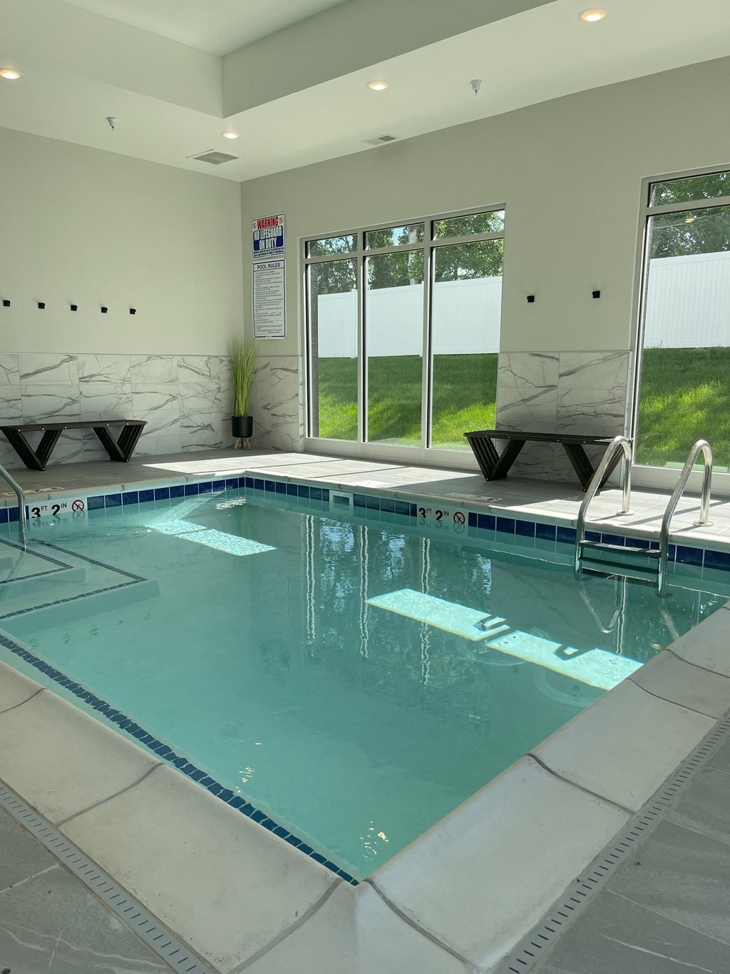 A large indoor swimming pool with a bench and a window.