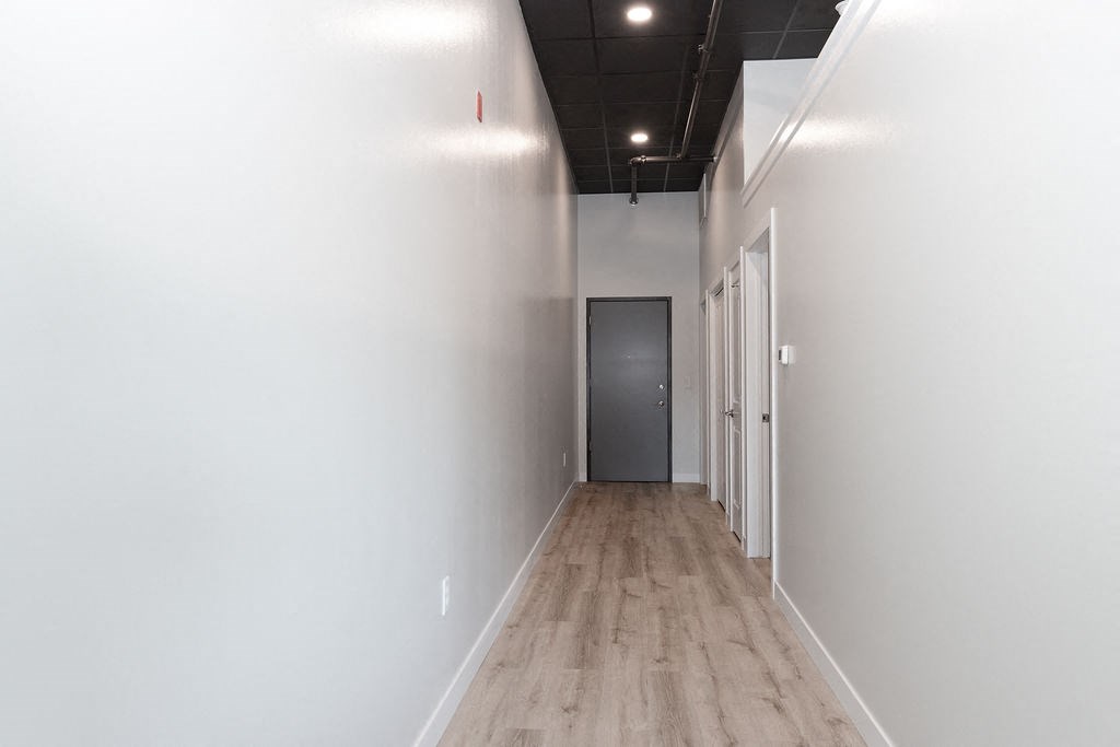 a hallway with white walls and wood floors and a door