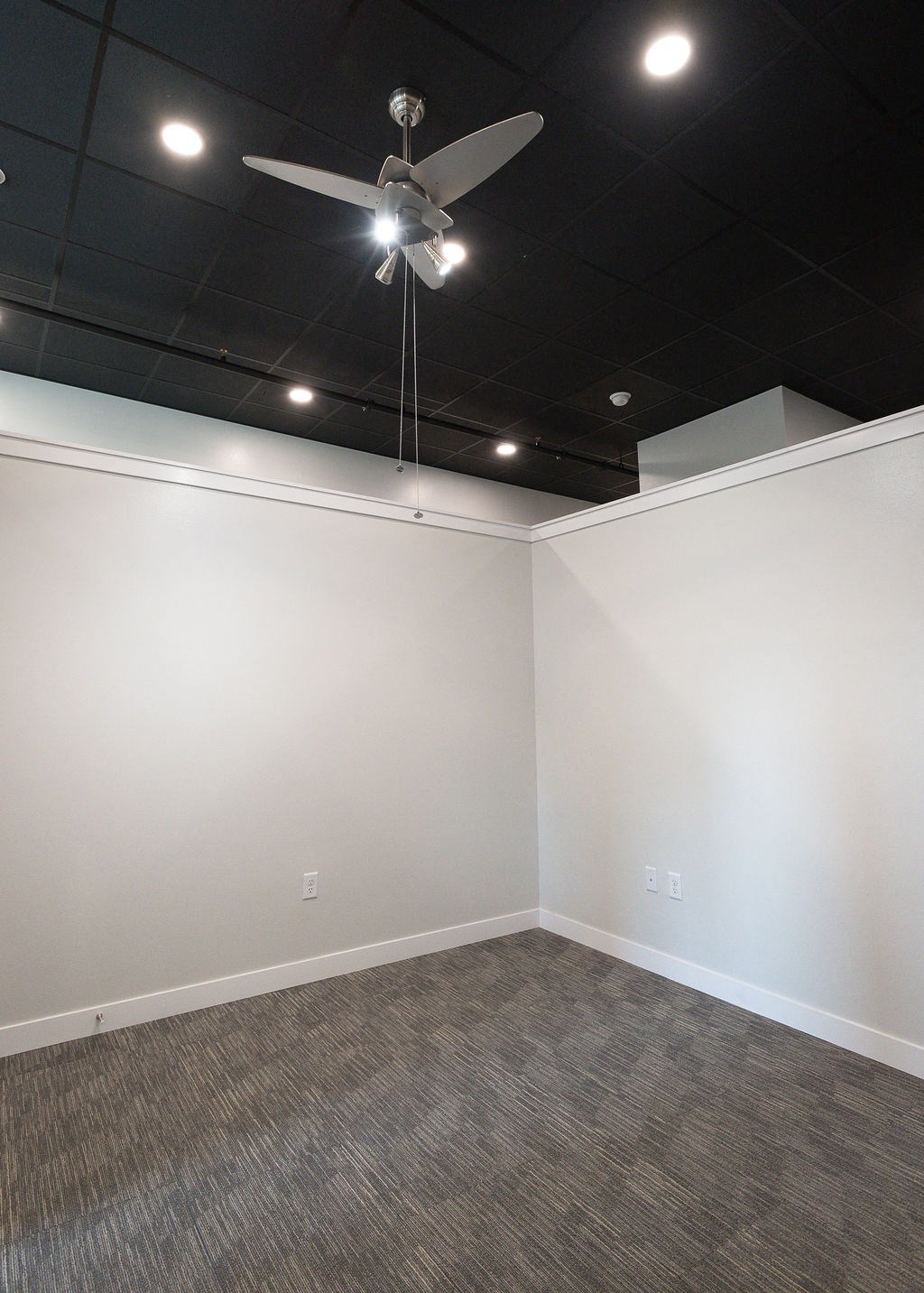 an empty room with a ceiling fan and white walls