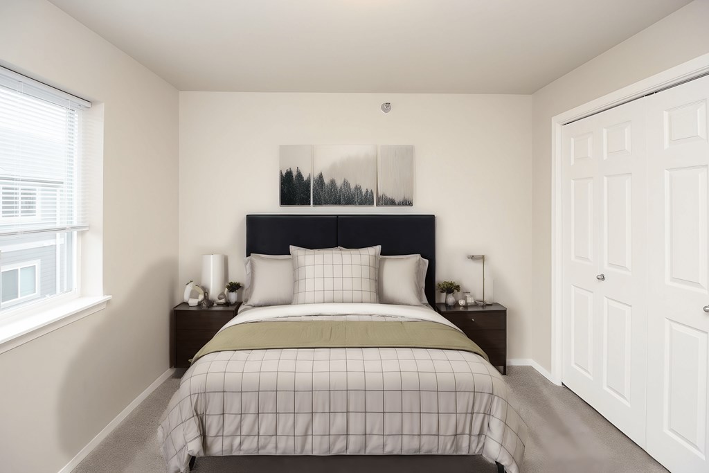 A bedroom with a bed, nightstands, and a window.