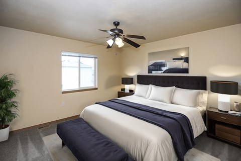 A bedroom with a large bed and a ceiling fan.