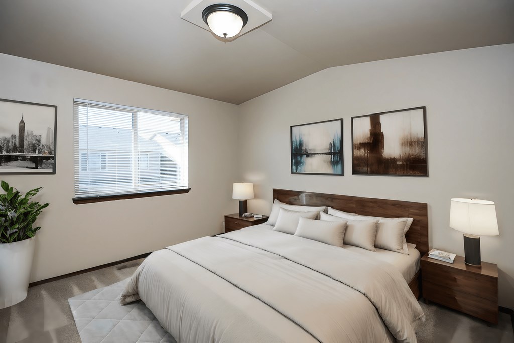 A bedroom with a large bed, two lamps, and three pictures on the wall.