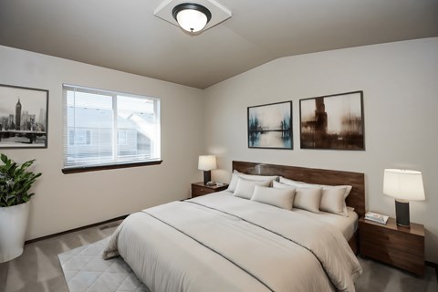 A bedroom with a large bed, two lamps, and three pictures on the wall.