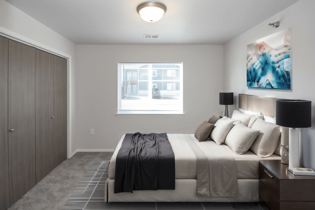 A bedroom with a bed, nightstand, and a painting on the wall.