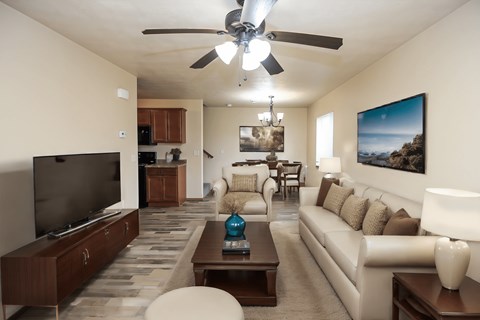 A living room with a television, couch, and a ceiling fan.