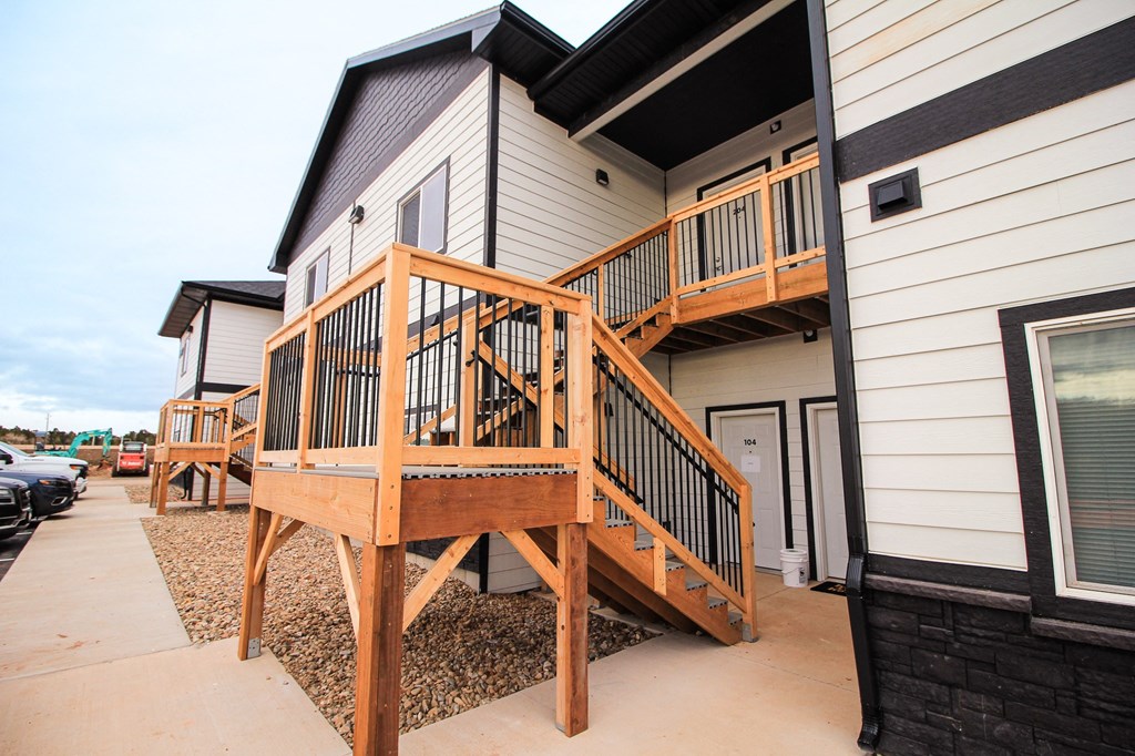 A wooden deck with a railing is in front of a house.