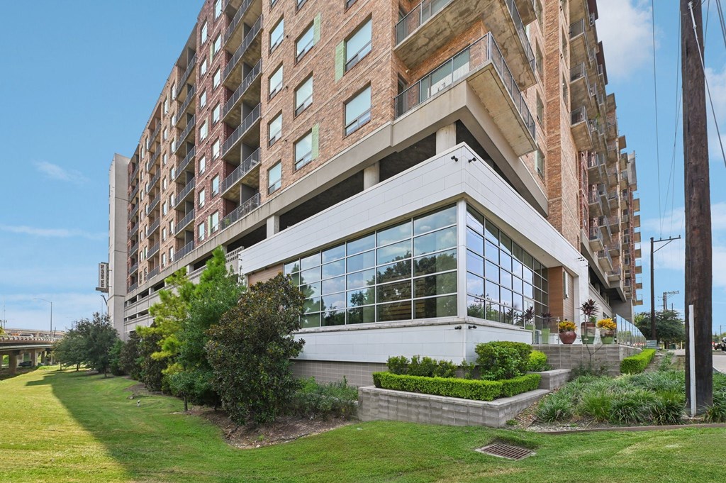 A modern building with a large glass facade and a landscaped front yard.