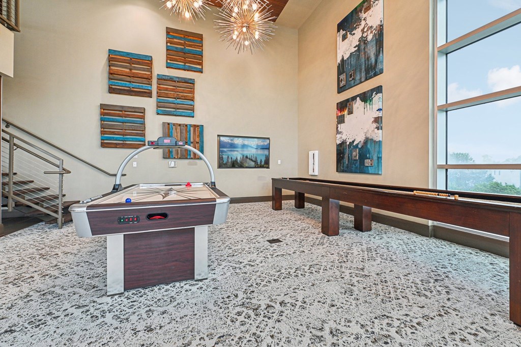 A pool table in a room with a carpeted floor and a staircase.