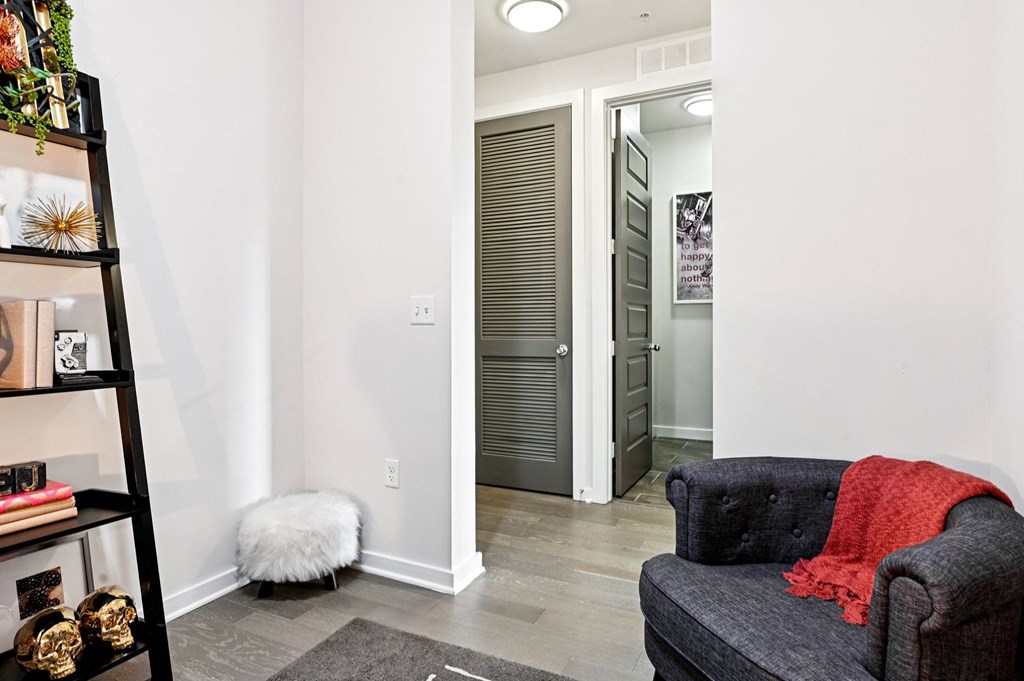 A black chair with a red blanket on it sits in a room with a white wall and a door.