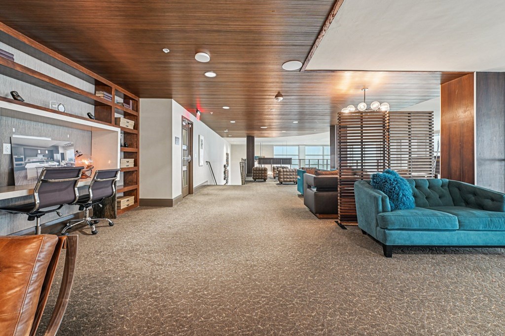 A modern office space with a long carpeted hallway and a variety of seating options.