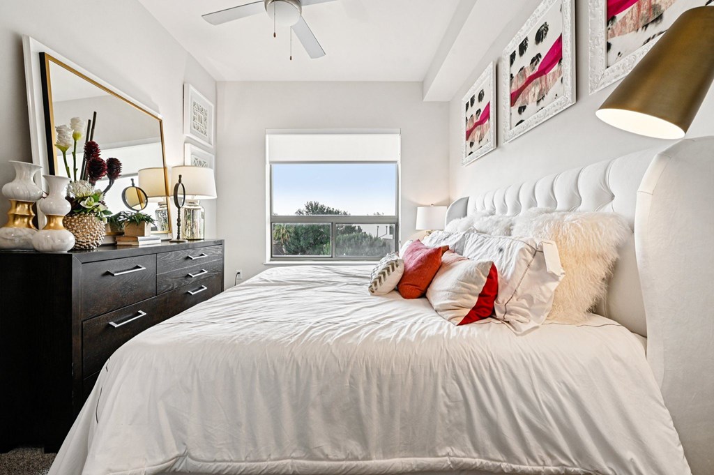 A bedroom with a large bed, a dresser, and a mirror.