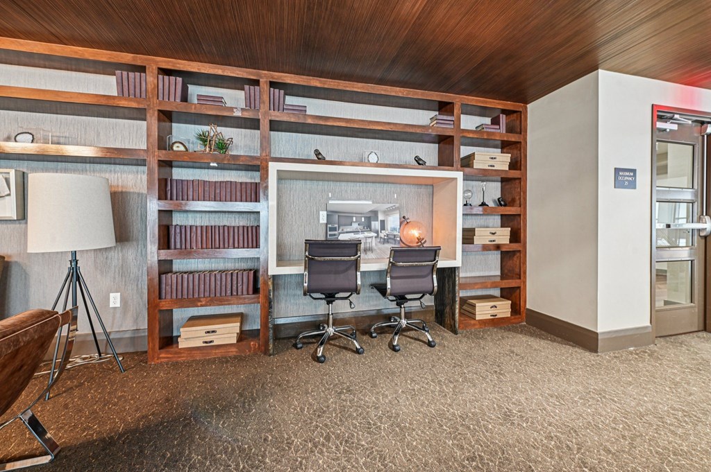 A room with a desk, chairs, and shelves filled with books.