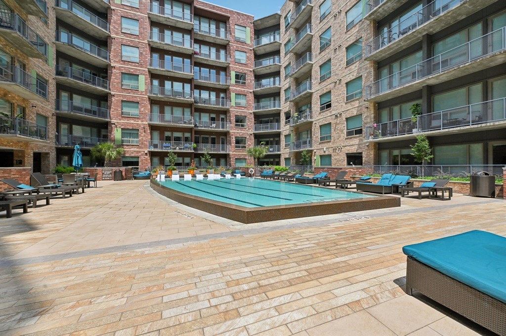 A large outdoor swimming pool surrounded by apartment buildings.