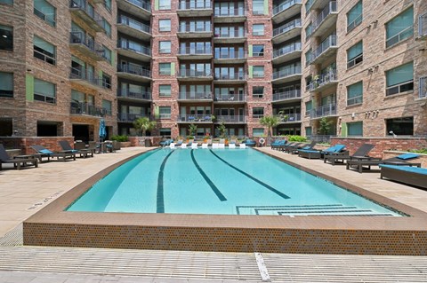 A large swimming pool in front of a multi-story apartment building.