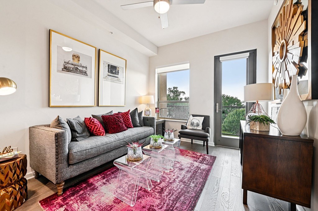 A living room with a grey couch, a coffee table, and a large window.
