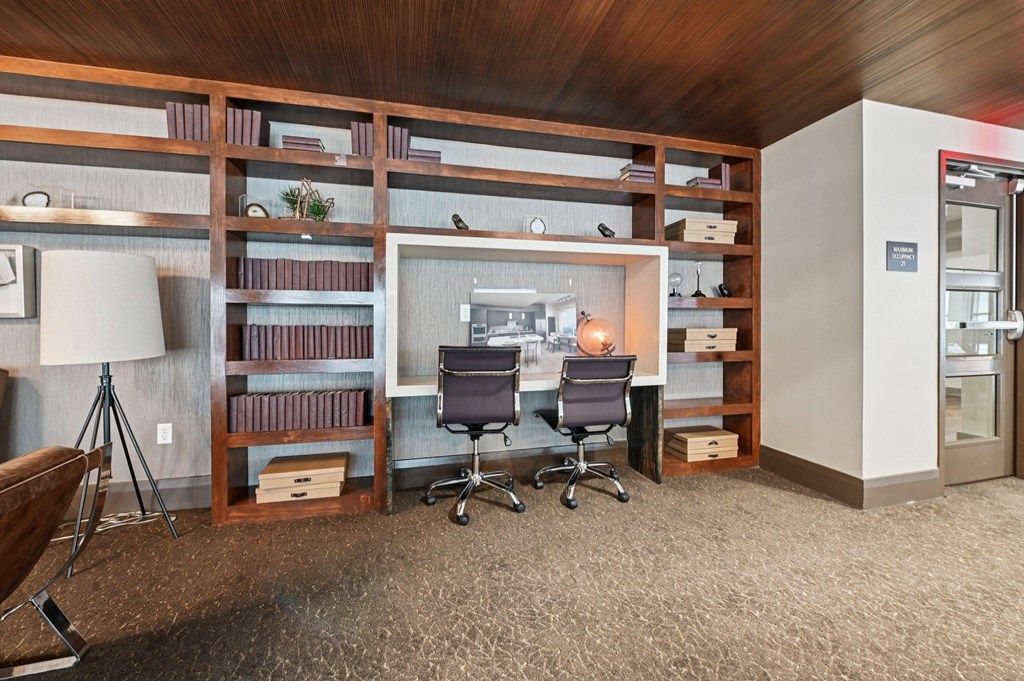A business center with a desk, chairs, and shelves filled with books.