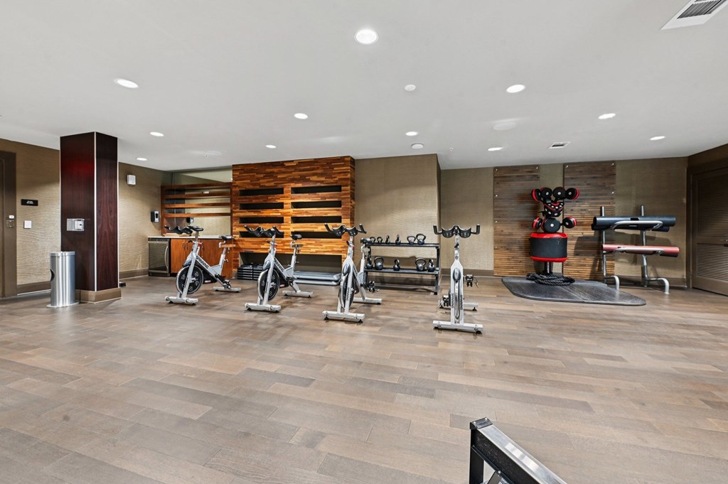 A gym with a variety of exercise equipment including treadmills, stationary bikes, and weight machines.