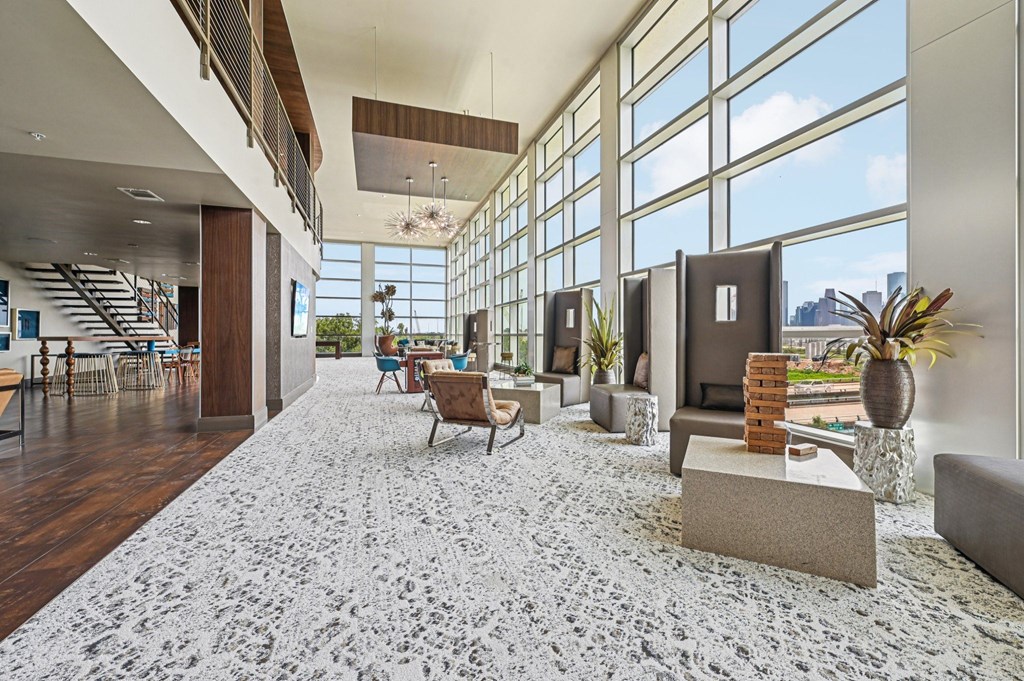 A large, modern living room with a staircase and a view of the city.
