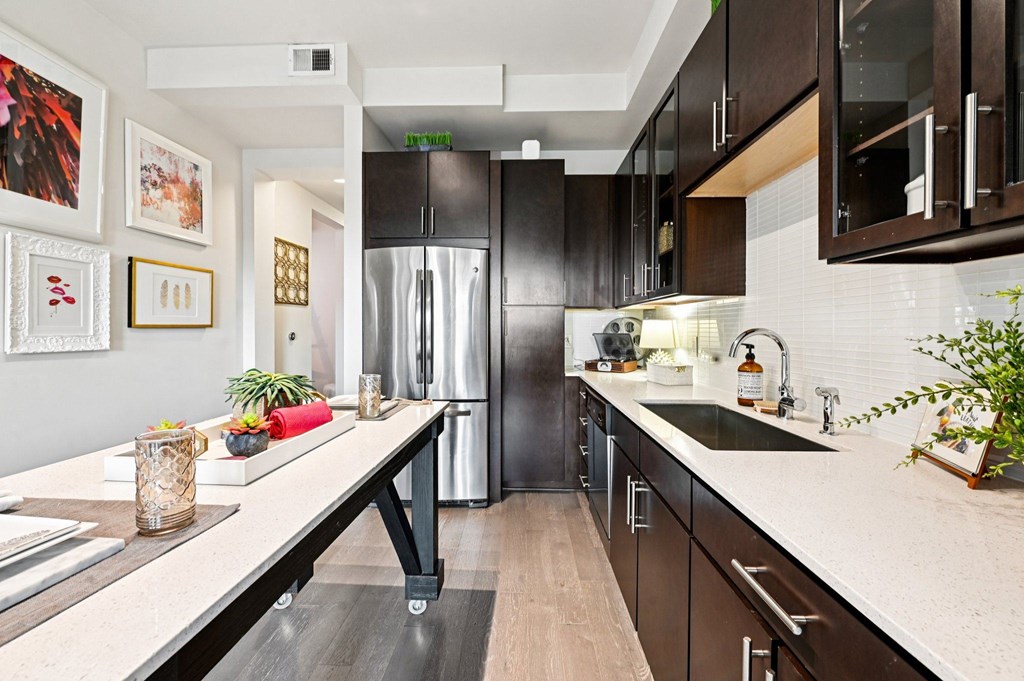A modern kitchen with dark brown cabinets and a white countertop.