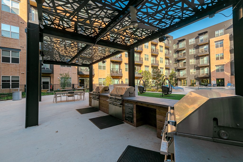 a patio with a grill and a table with chairs and a building in the background