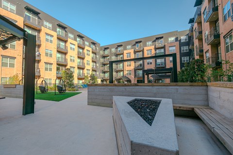 A modern courtyard with a bench and a table surrounded by buildings.