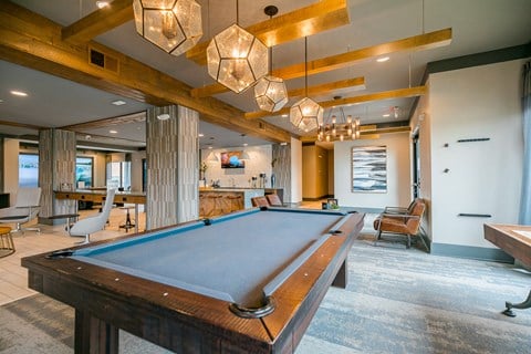 a pool table in a living room with a bar and couches