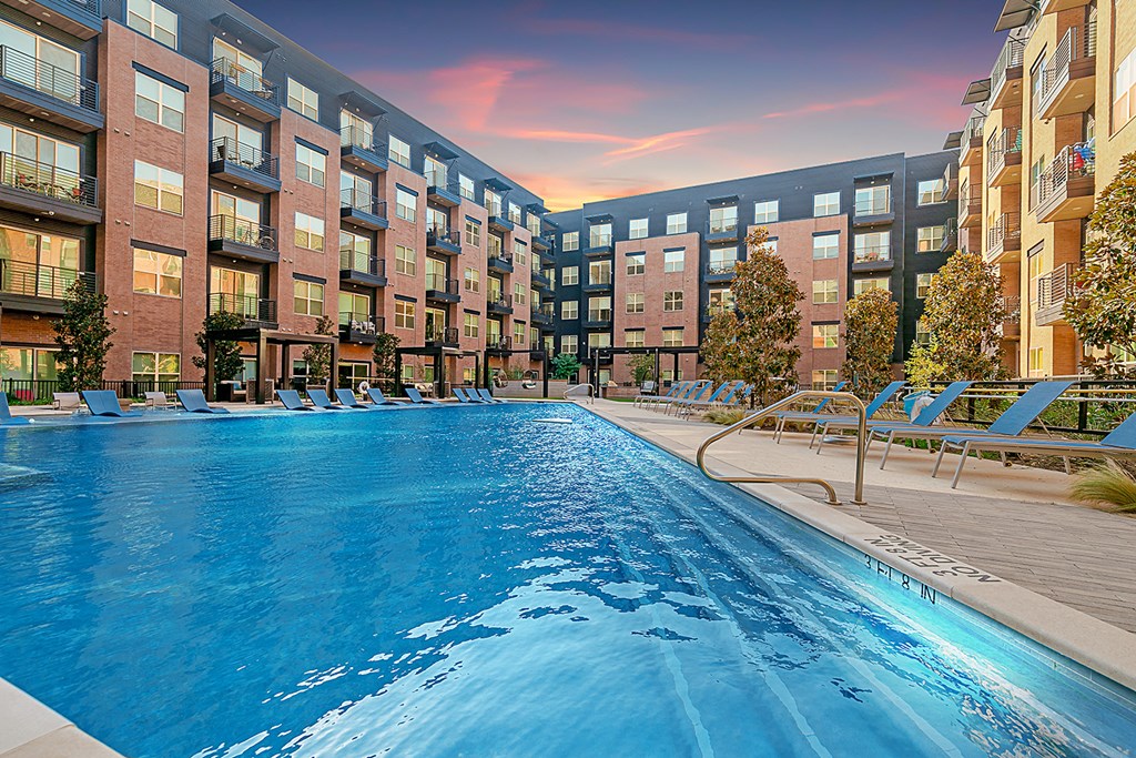 a swimming pool in front of an apartment building at sunset