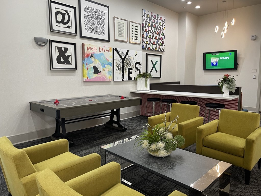 A room with a pool table, chairs, and pictures on the wall.