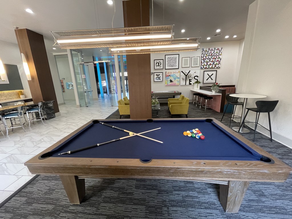 A pool table in the middle of a room with a glass wall in the background.