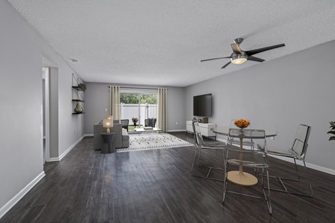 A living room with a ceiling fan and a dining table set up.
