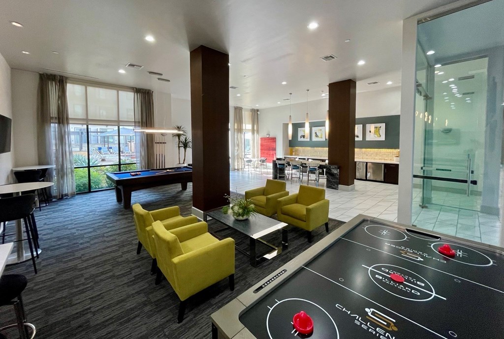 A modern room with a shiny black table in the middle and yellow chairs.