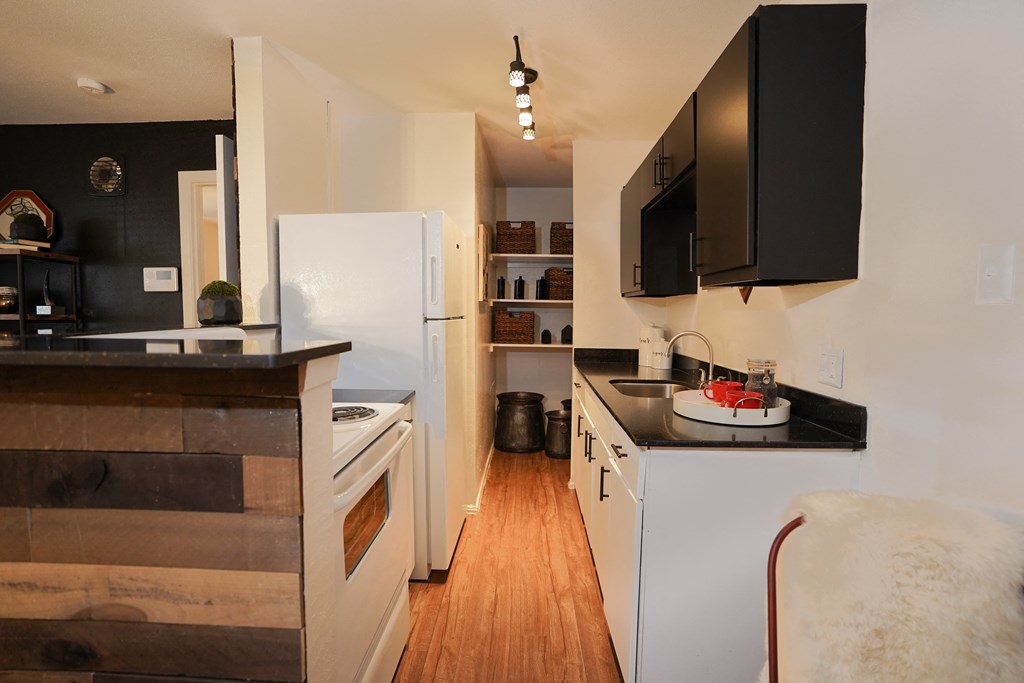a kitchen with white appliances and black countertops