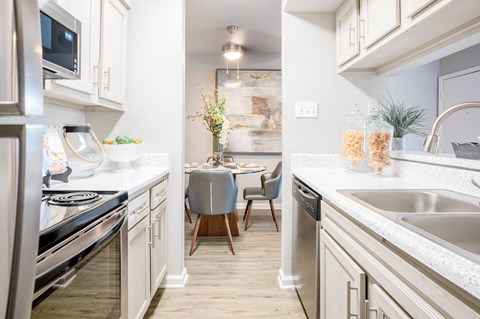 A kitchen with a stove, sink, and a dining table with chairs.