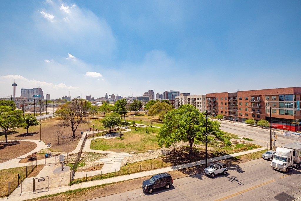 A city street with cars and a green park area.
